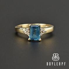 Beautifull medium blue natural aquamarine glows in this vintage 14K yellow gold ring with diamond accents. The 1.35 carat emerald cut aquamarine is set off the finger with four prongs and has three round diamonds on each side. In ancient lore, Aquamarine was believed to be the treasure of mermaids and was used by sailors as a talisman of good luck, fearlessness, and protection.