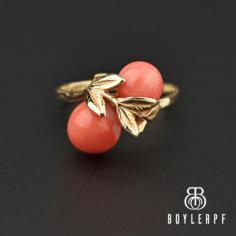 Mediterranean salmon orange-colored cabochon coral balls bypass one another with a gold leaf branch in the center to form this chic estate ring.  The hand-fabricated 14K gold ring is elegant and sleek ring that enables it to blend well with other pieces and a standout all on its own!
