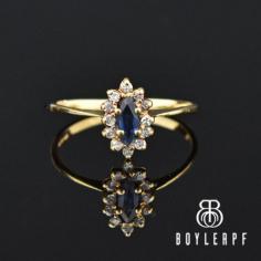 Beautifully framed by a halo of sparkling white diamonds, this stunning vintage sapphire engagement ring is handcrafted in 10K gold. Centered on a marquis shaped natural blue sapphire, the ring is an emulation of classic early-twentieth-century Edwardian era. The sapphire is set high with the diamonds in an open work base that allows light to shine through. 